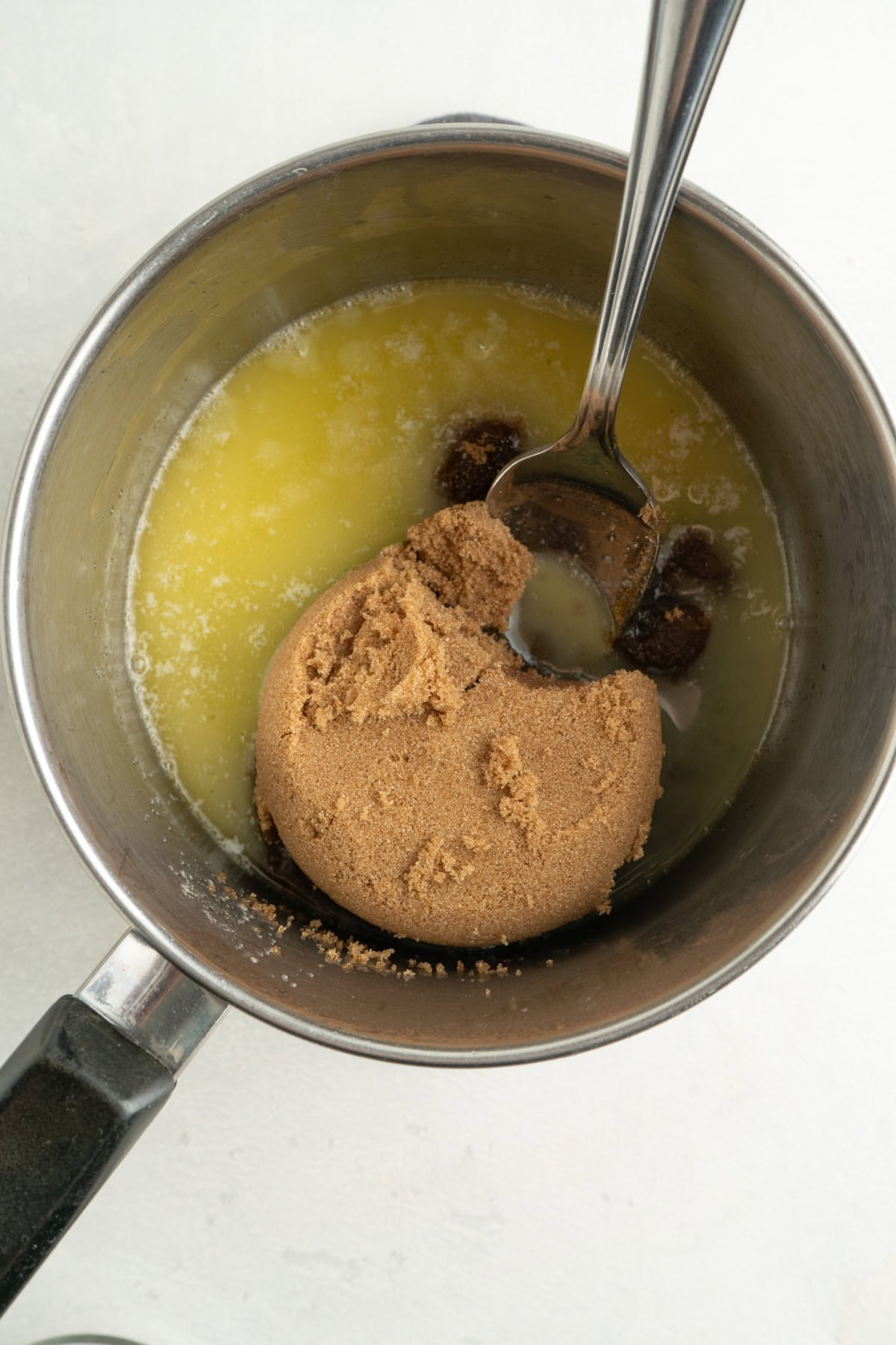 Melted butter and brown sugar in a po with a spoon.