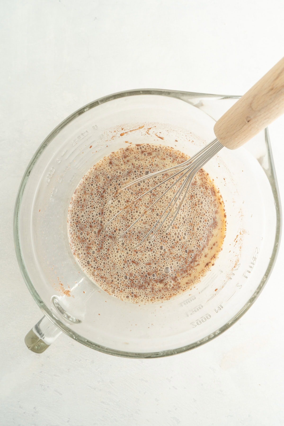 The egg and spice mixture for french toast in a bowl with a whisk.