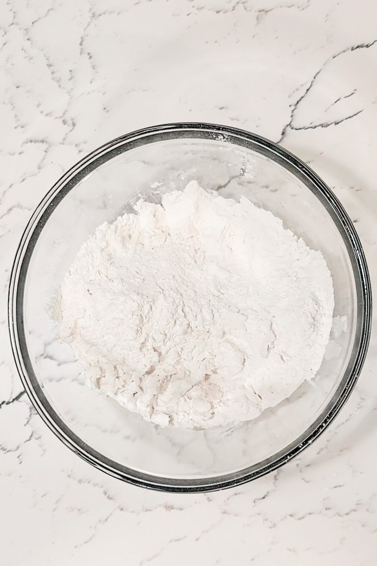 Shortening and flour cut in to form an oatmeal like texture in a large bowl.