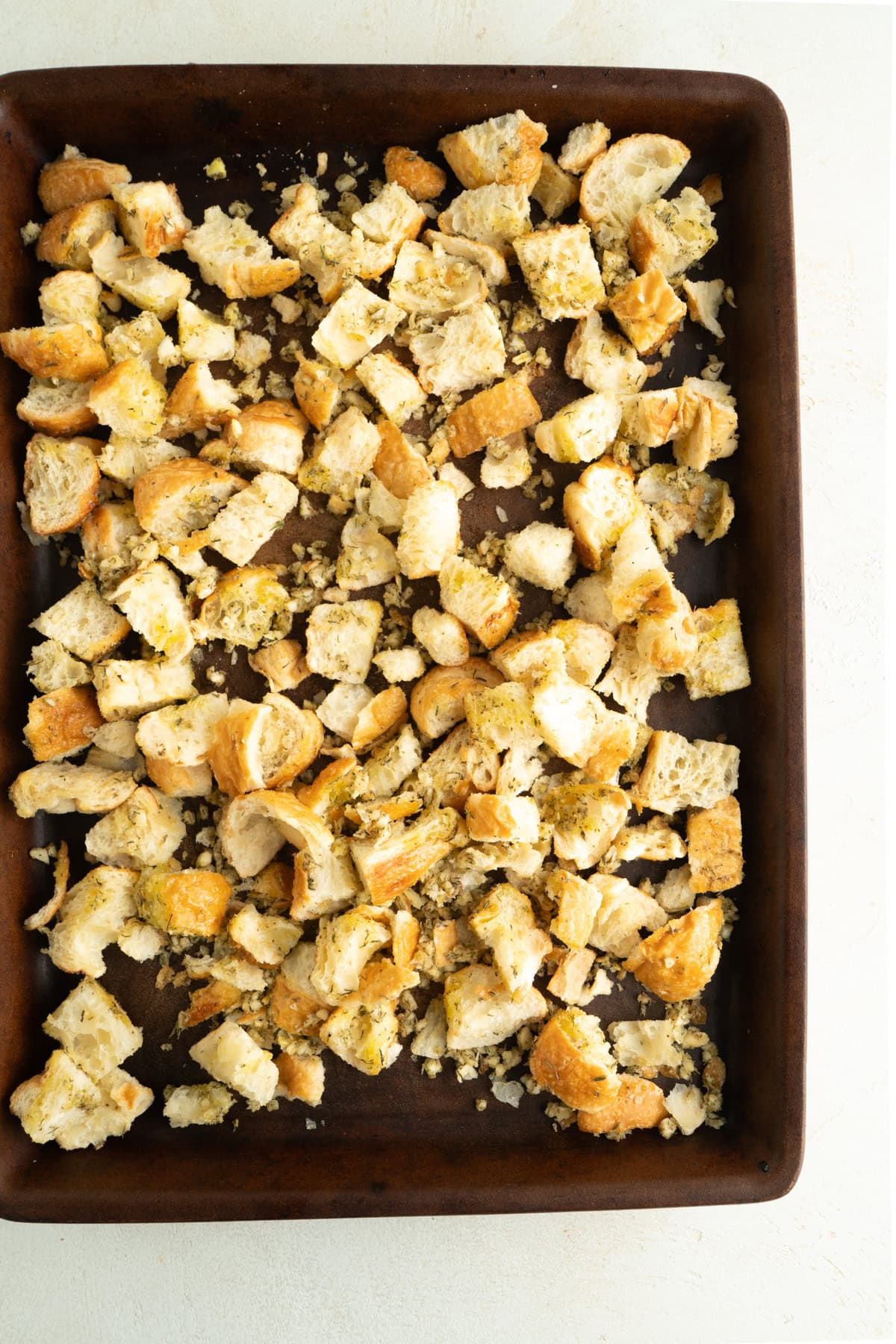A baking sheet of seasoned cubed croissants.