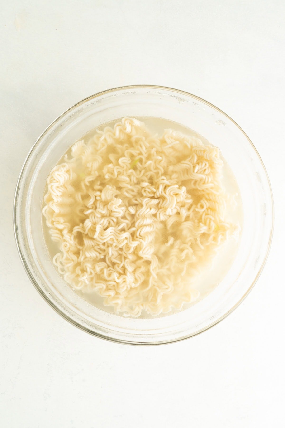 A bowl of ramen noodles soaking in boiling water.