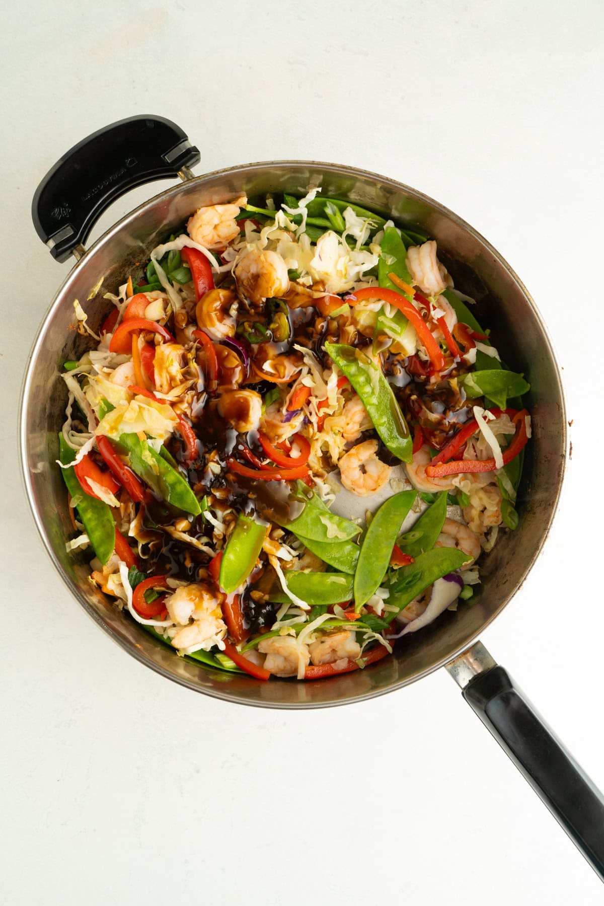 Teriyaki sauce added to a pan of shrimp stir fry.