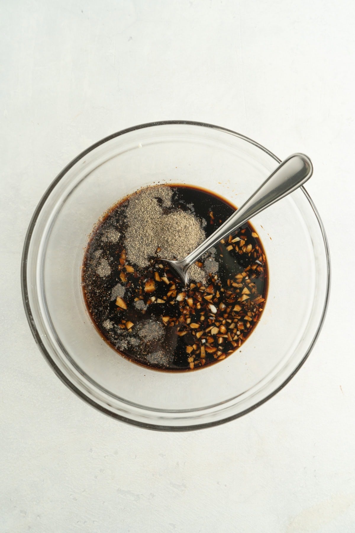 A bowl filled with honey, garlic, soy sauce, and black pepper.