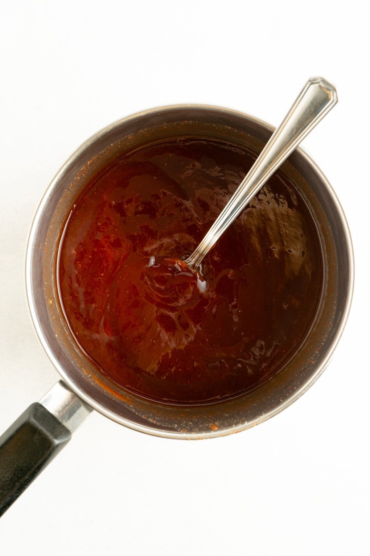 Barbecue sauce in a pot with a spoon.