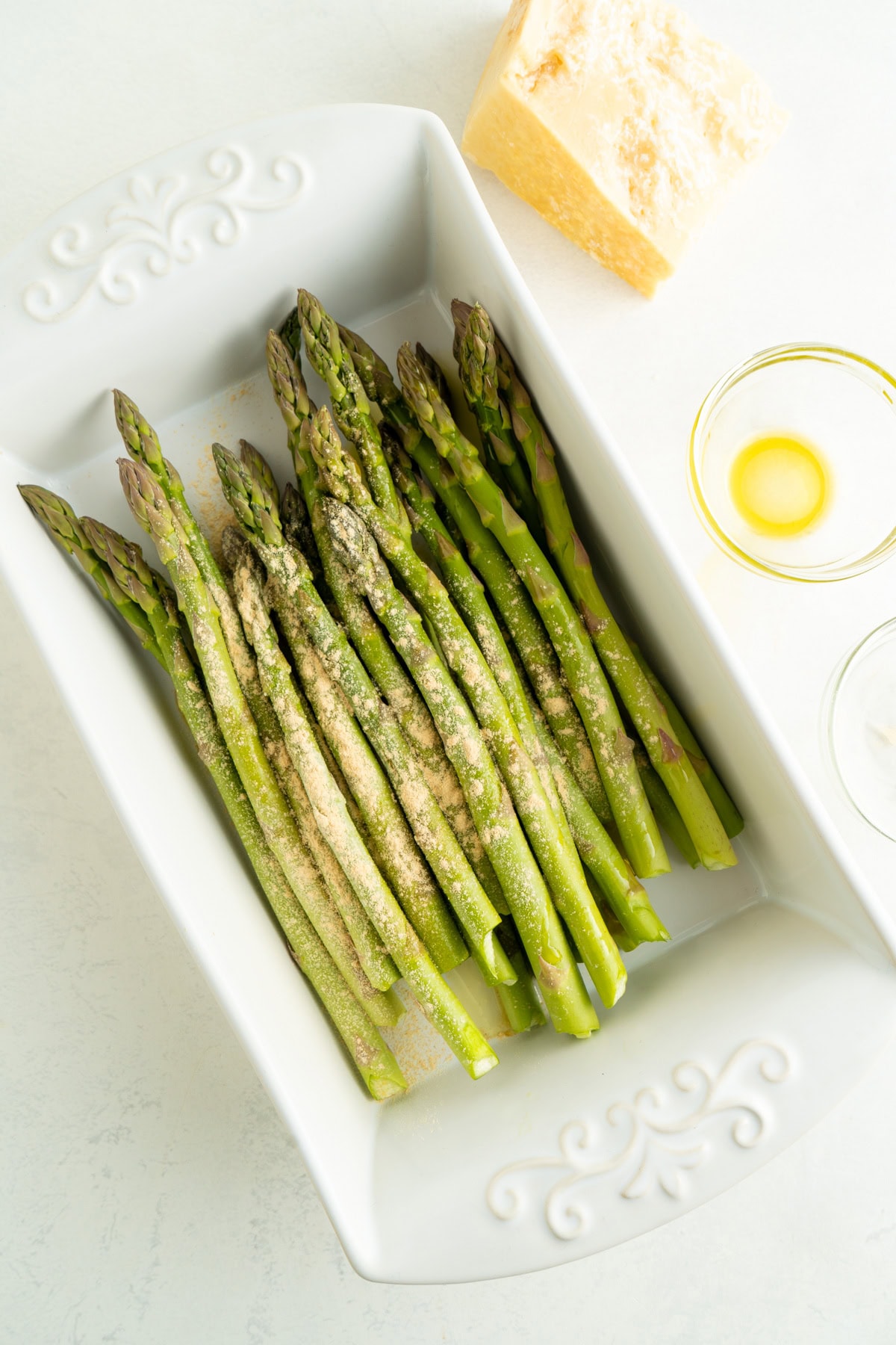 Asparagus in a dish topped with garlic powder and olive oil.