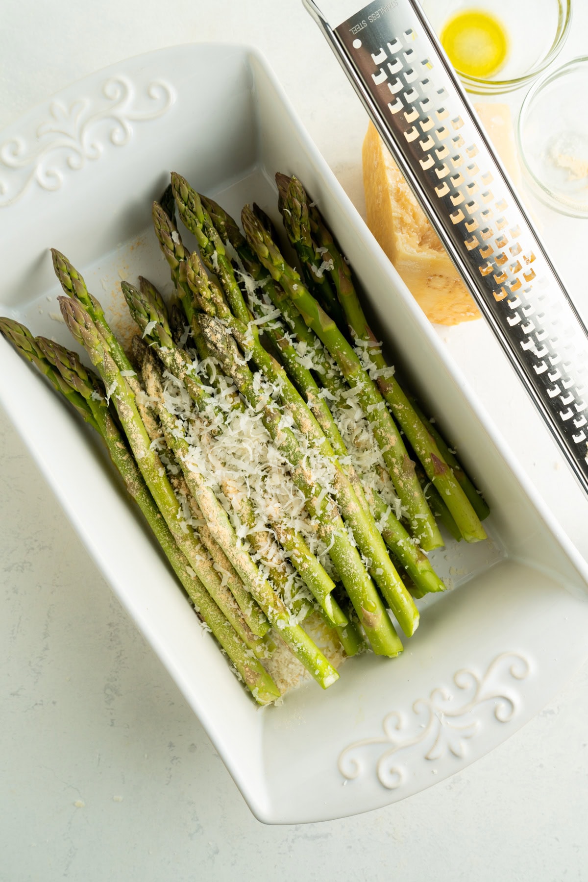 A dish of asparagus topped with fresh shredded parmesan.