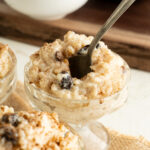 Rice pudding in a pedestal sundae cup with a spoon in the centre.