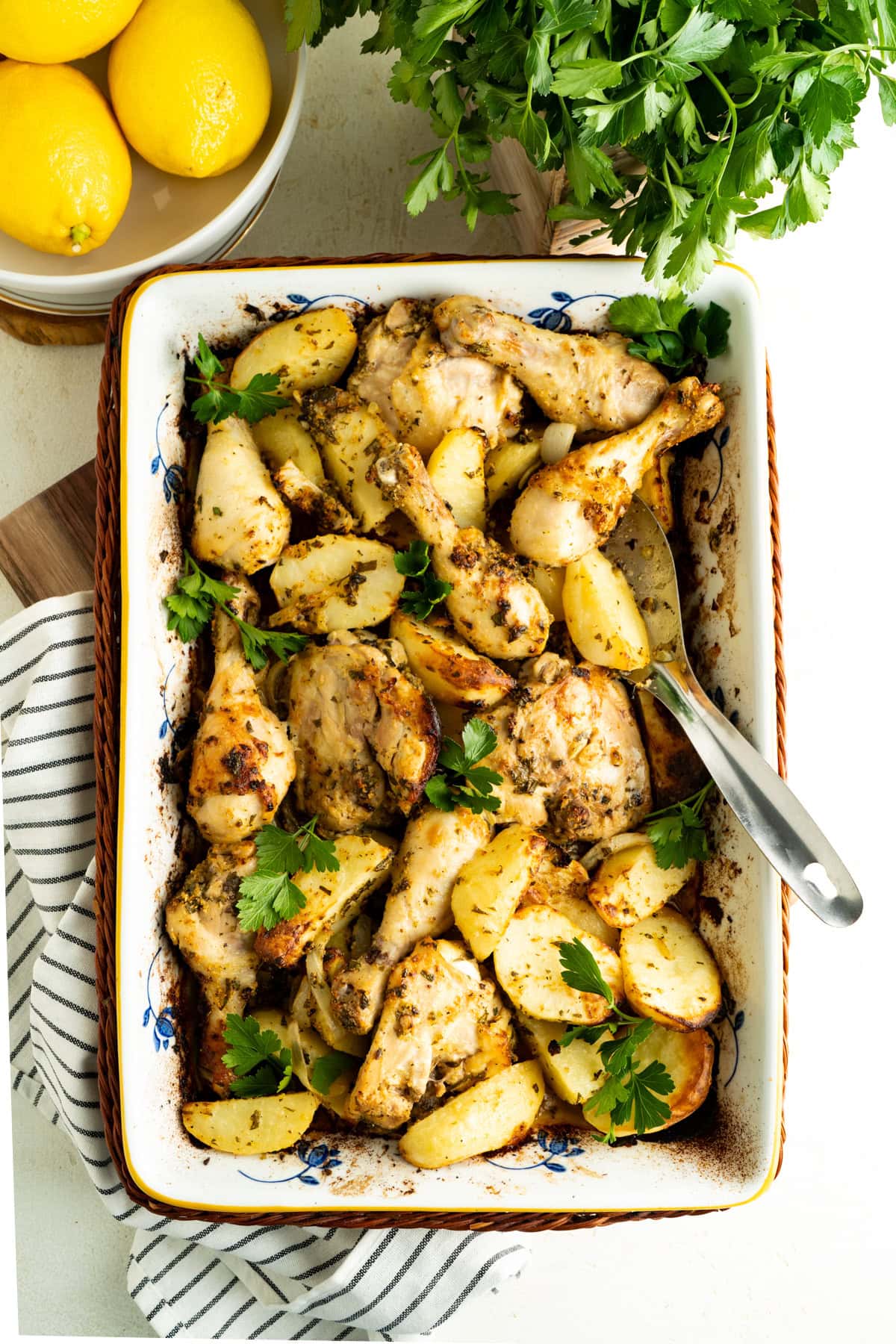 Overhead shot of a pan of lemon chicken and potatoes on a table setting.