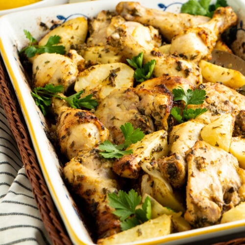 A pan of roasted lemon chicken and potatoes with parsley.