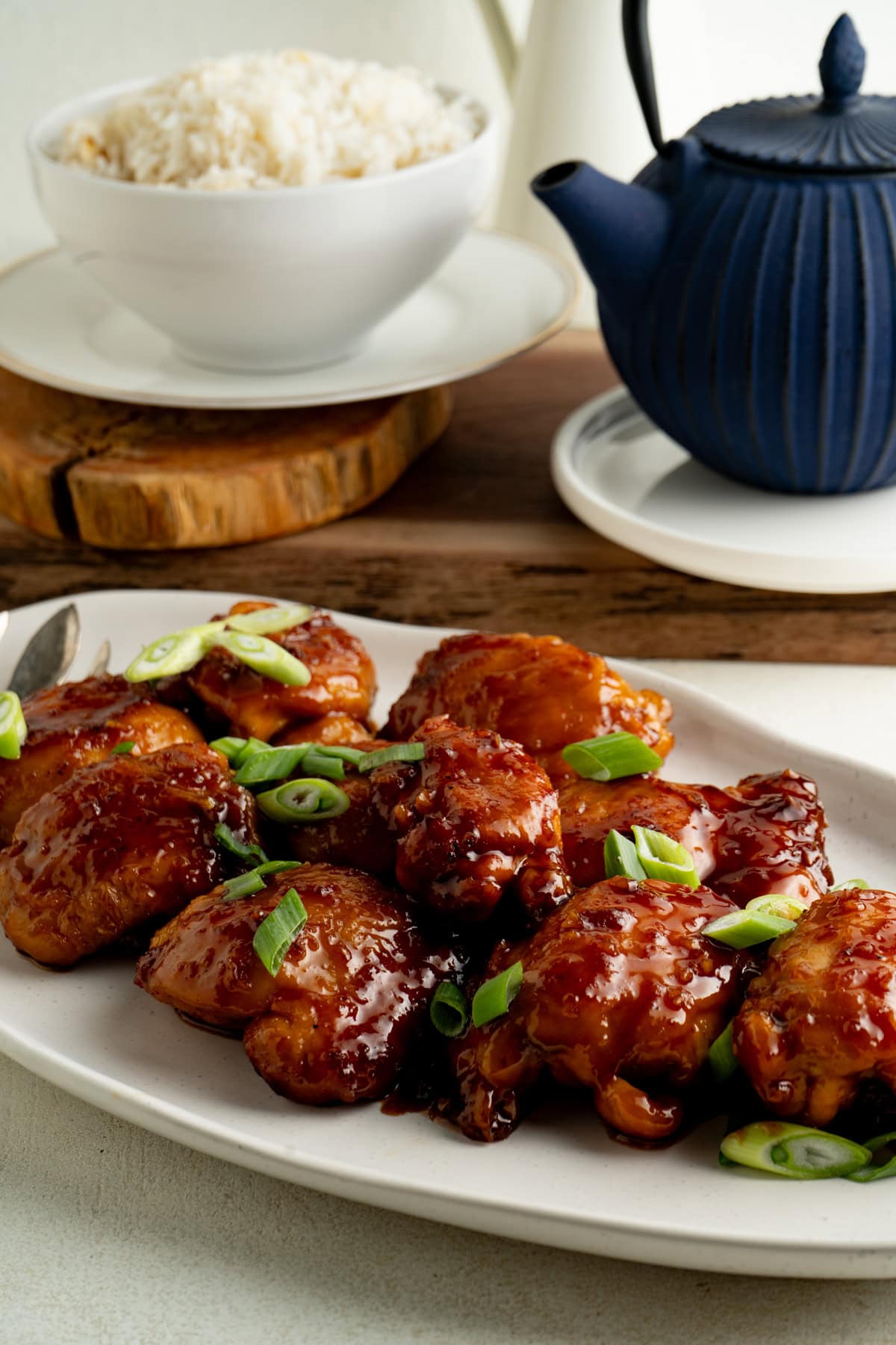 A platter of honey garlic chicken thighs with sliced green onion.