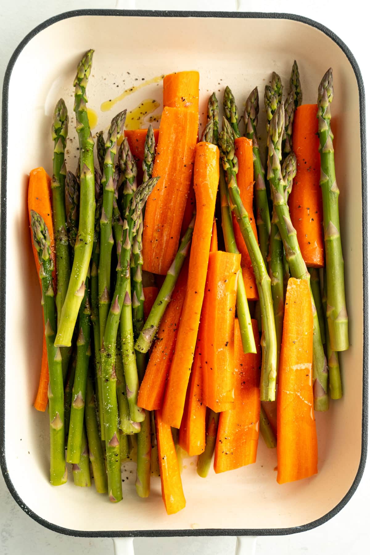 Carrots and asparagus in a roasting pan with olive oil, salt and pepper.
