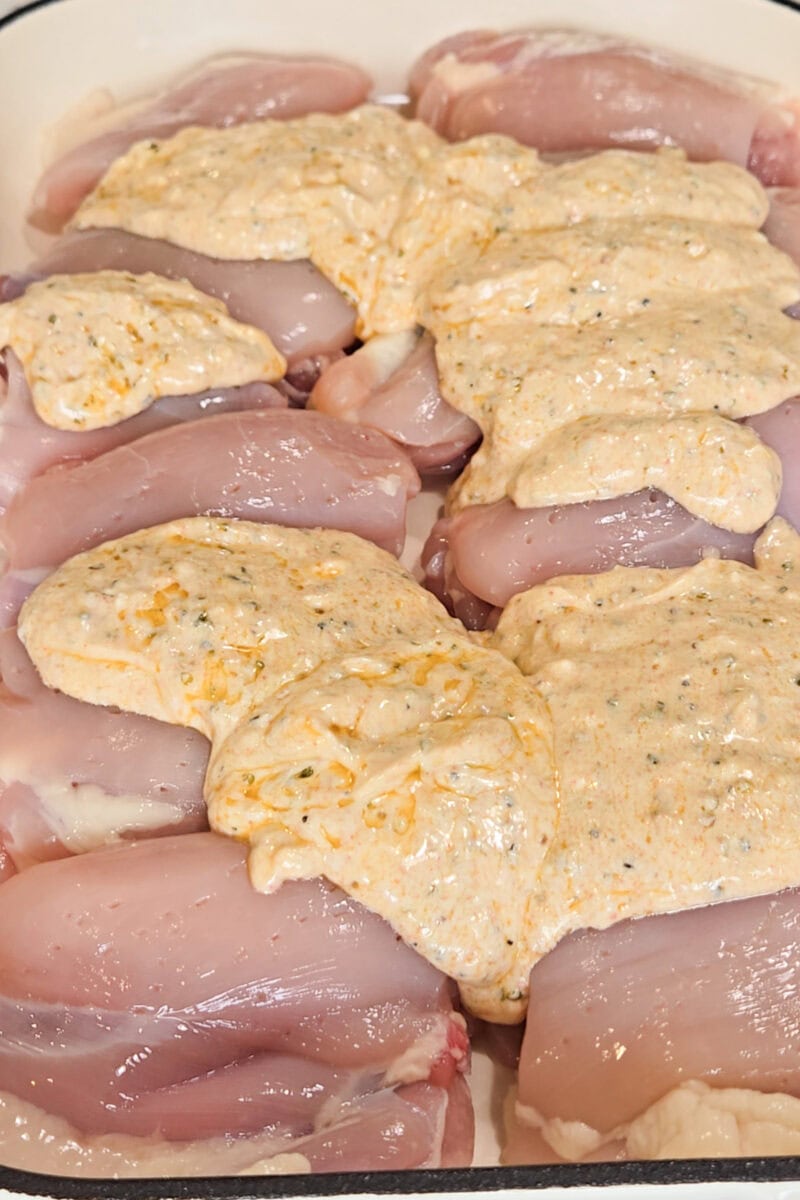 Chicken thighs in a casserole dish with marinade poured over top.