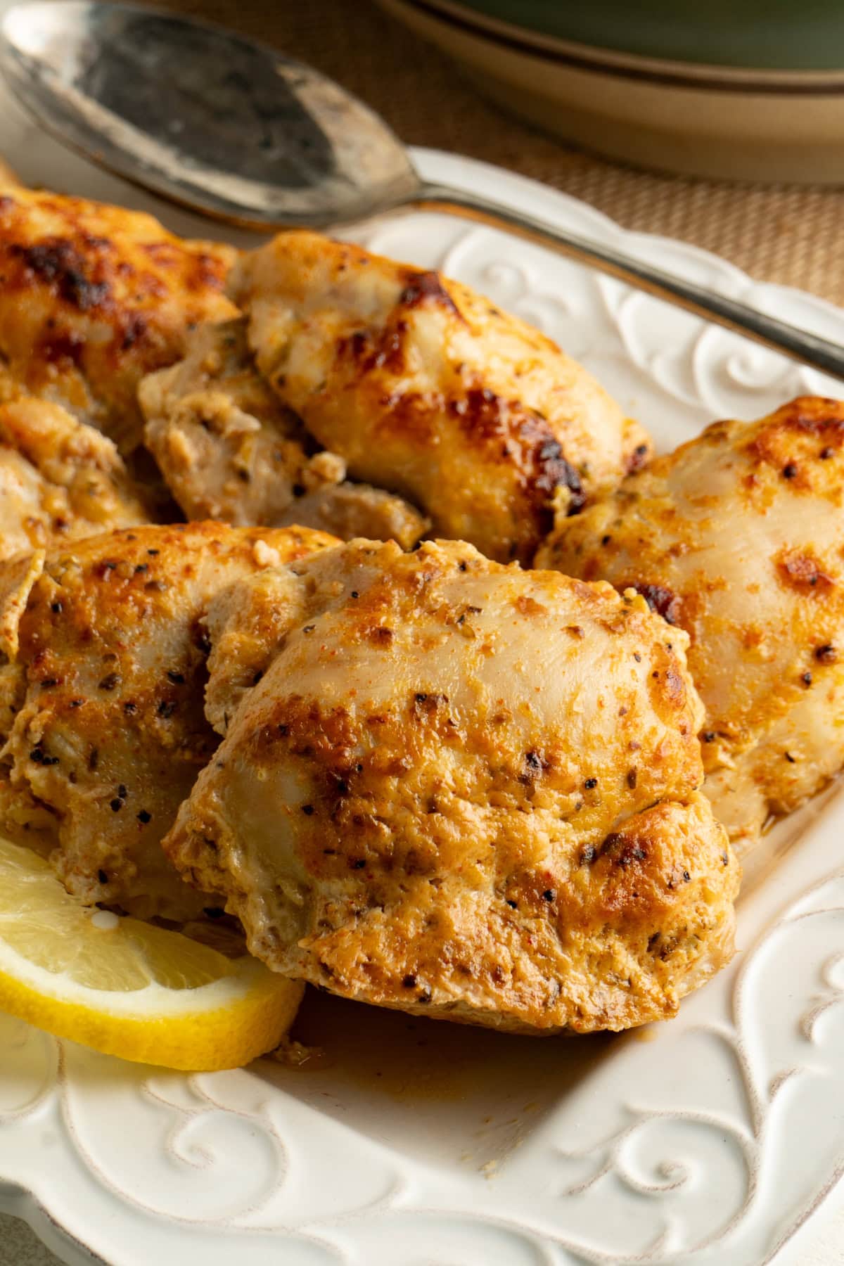 Close up of a Greek marinated chicken thigh with a slice of lemon.