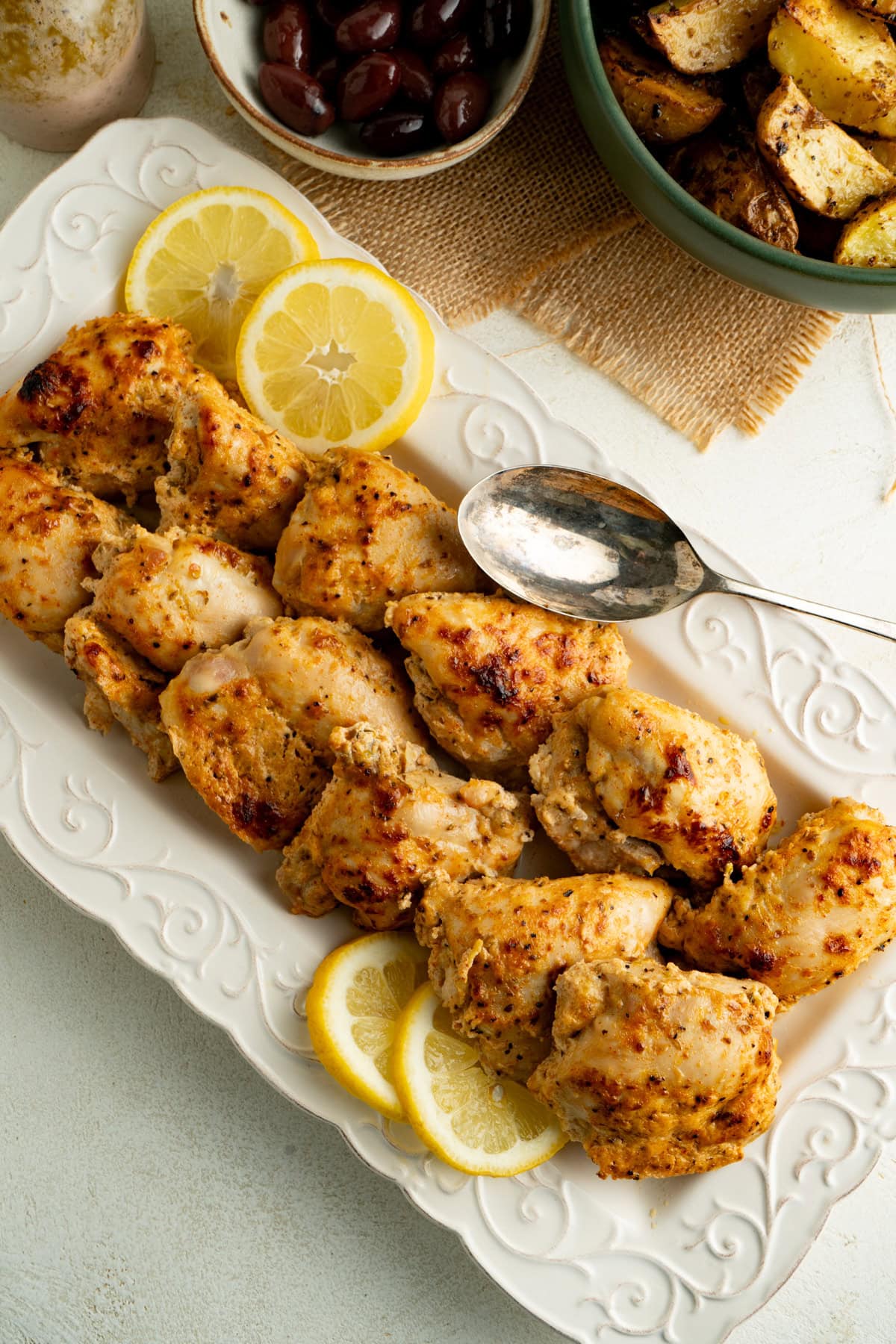 A platter of baked chicken thighs on a dinner table.