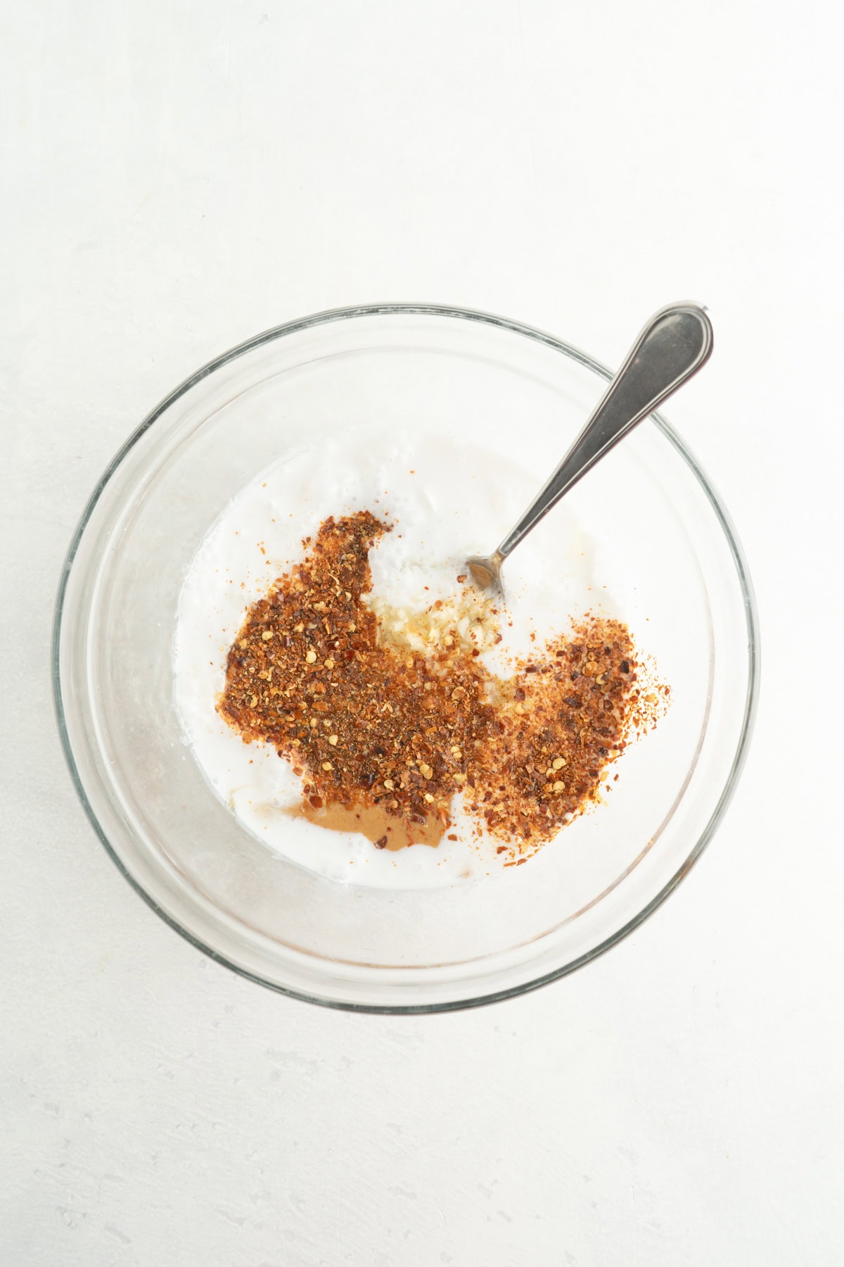 A bowl of peanut sauce ingredients and a spoon.