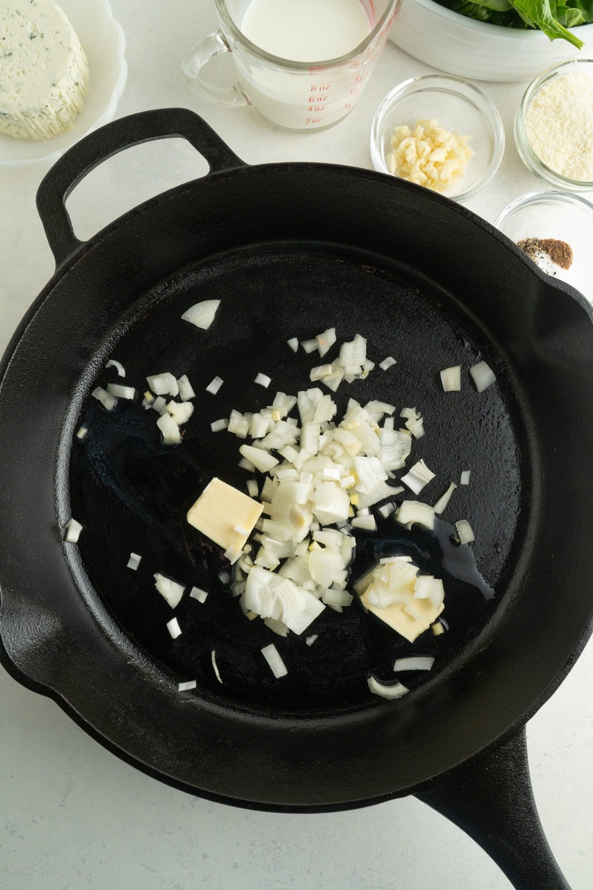 Butter and onions in a cast iron pan being cooked.