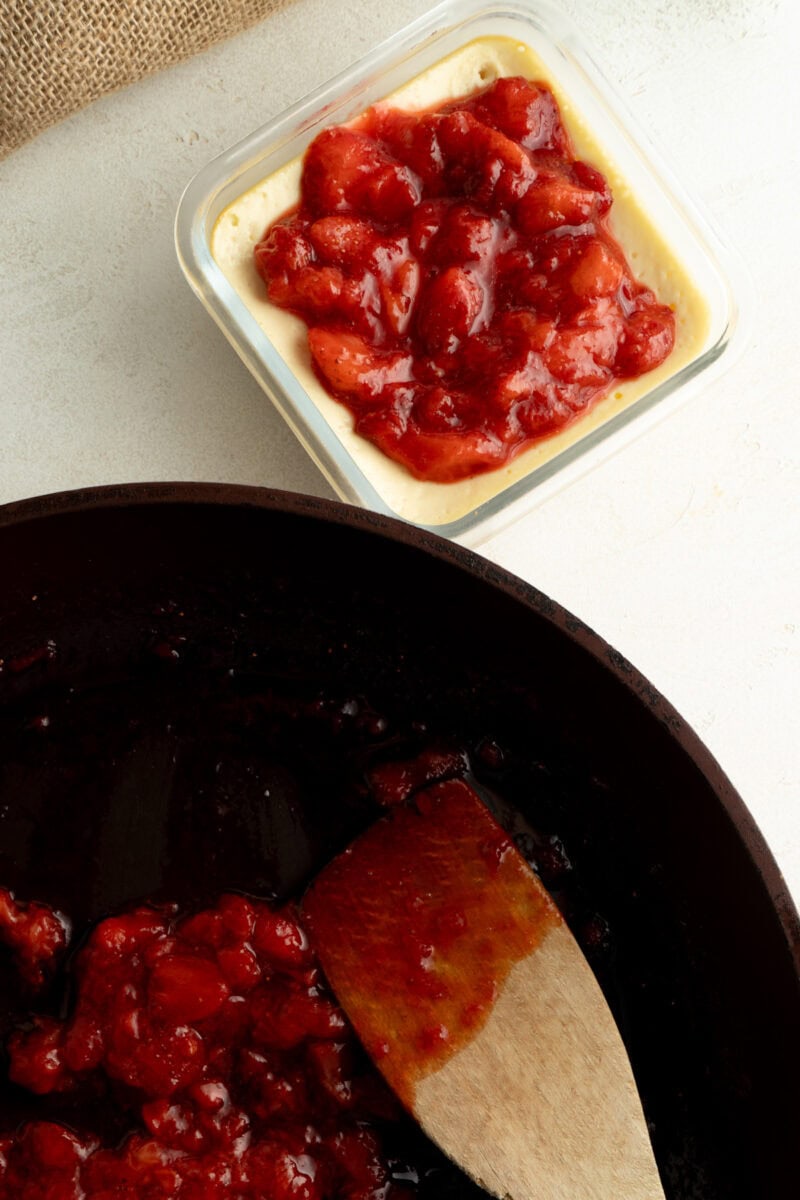 A cheesecake having a strawberry topping added on top.