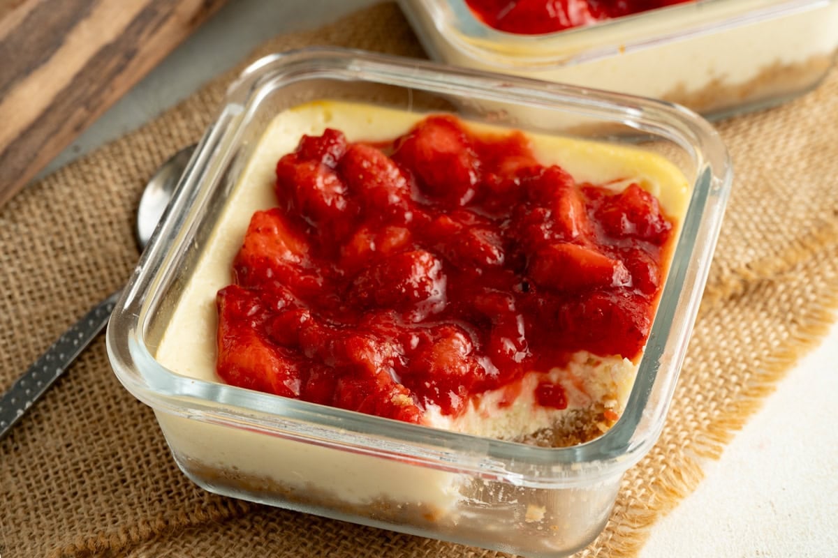 A mini cottage cheese cheesecake topped with strawberries with one bite missing.
