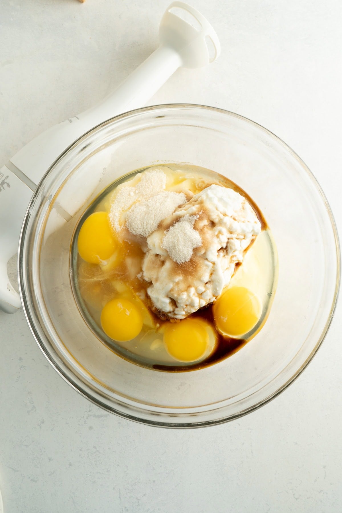 A bowl of eggs, cottage cheese, yogurt, vanilla and sweetener.