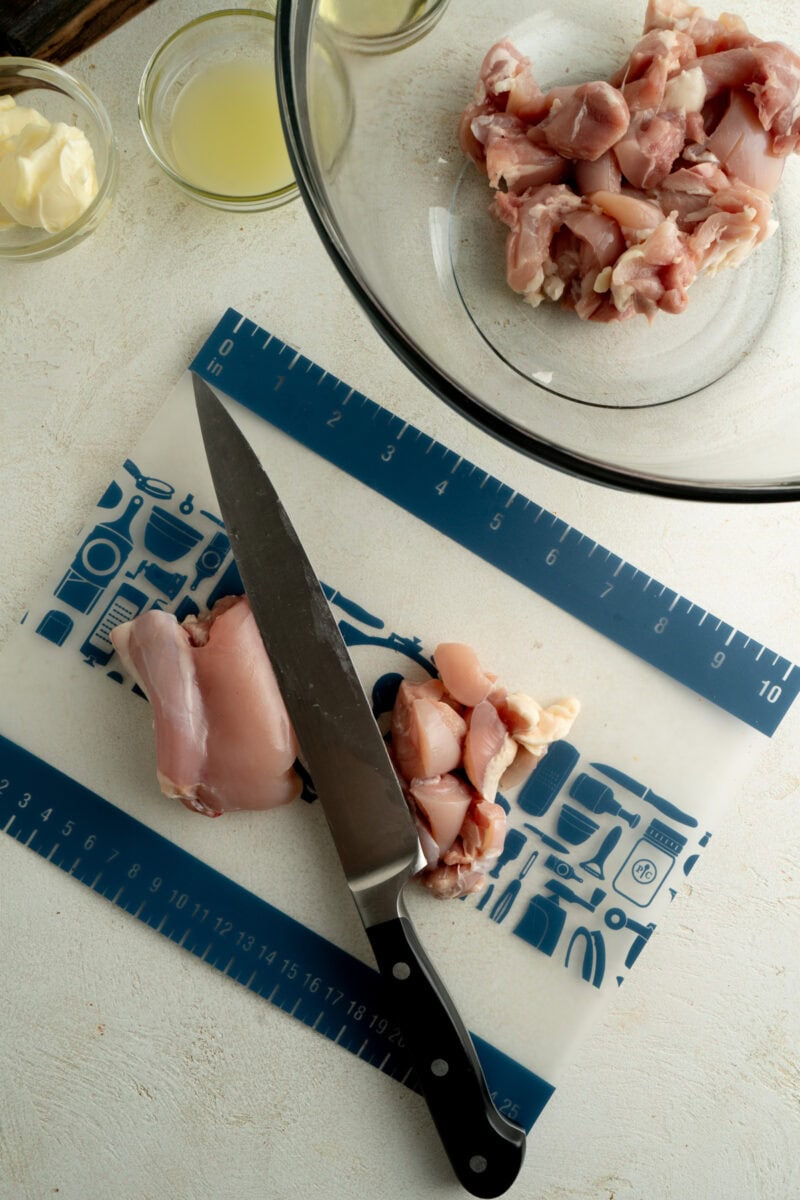 Chicken thighs being cut into small cubes.