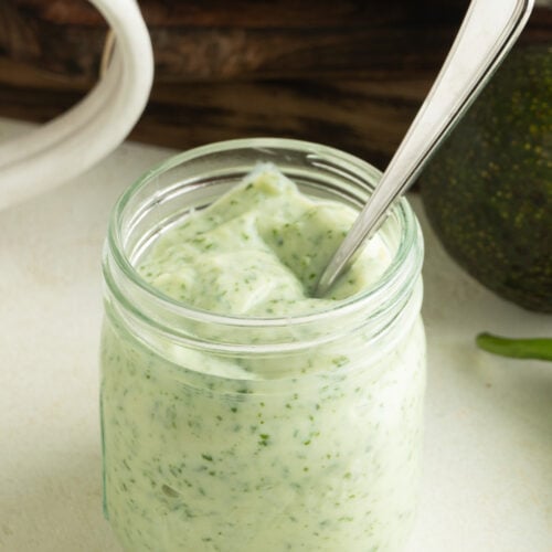 A jar or jalapeno ranch dressing with a spoon inside.