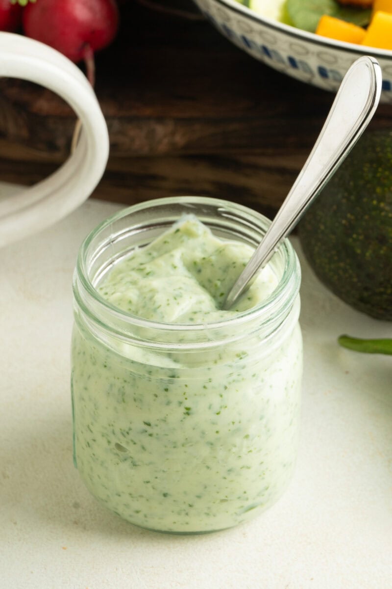 A jar or jalapeno ranch dressing with a spoon inside.