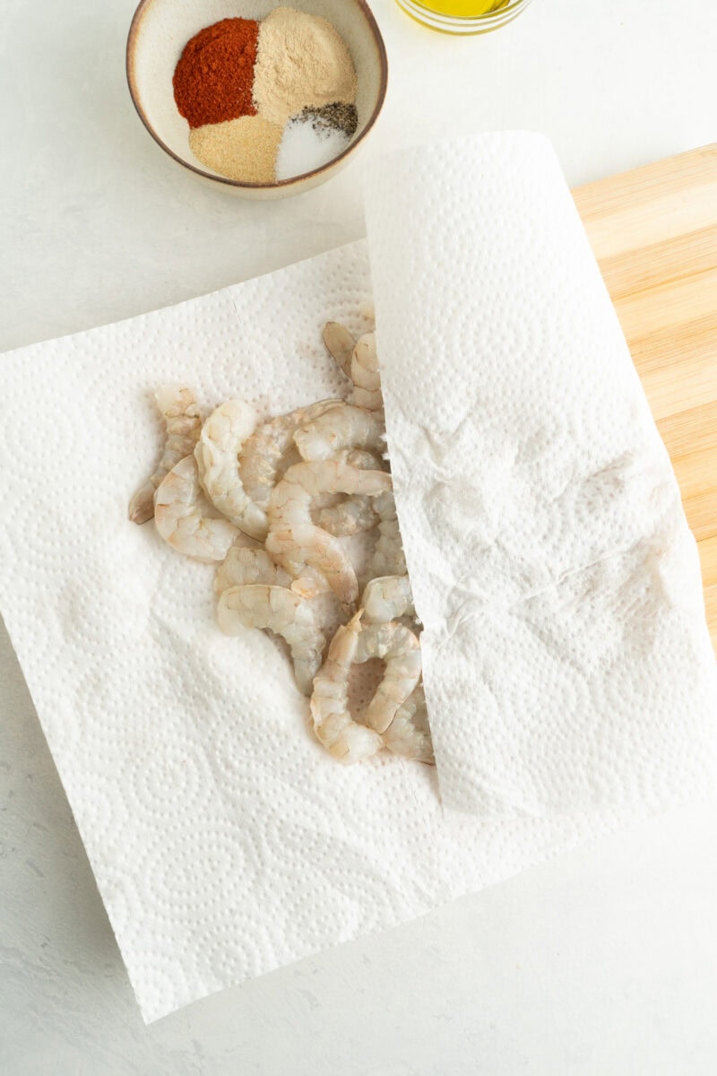 Shrimp on a paper towel being patted dry.