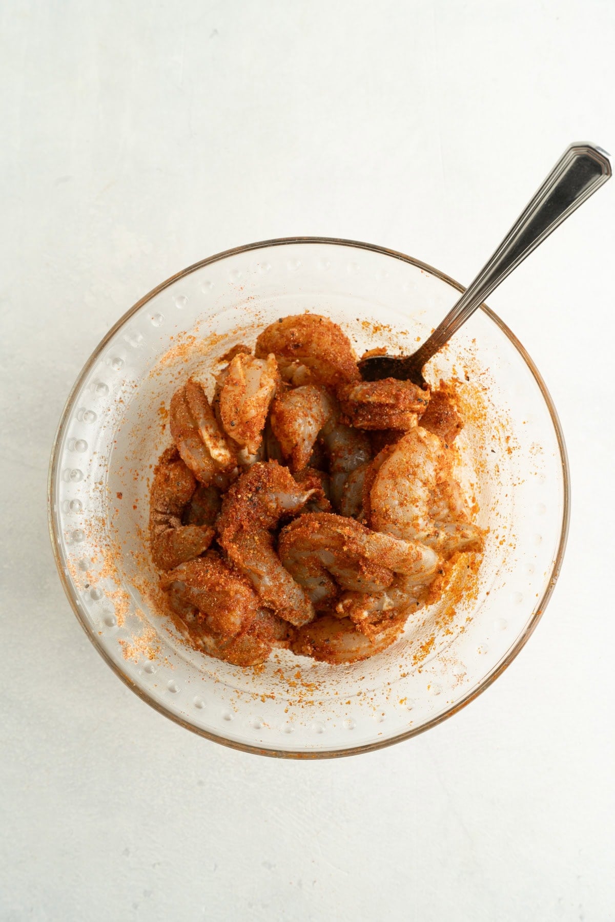 Shrimp in a bowl being mixed with spices.