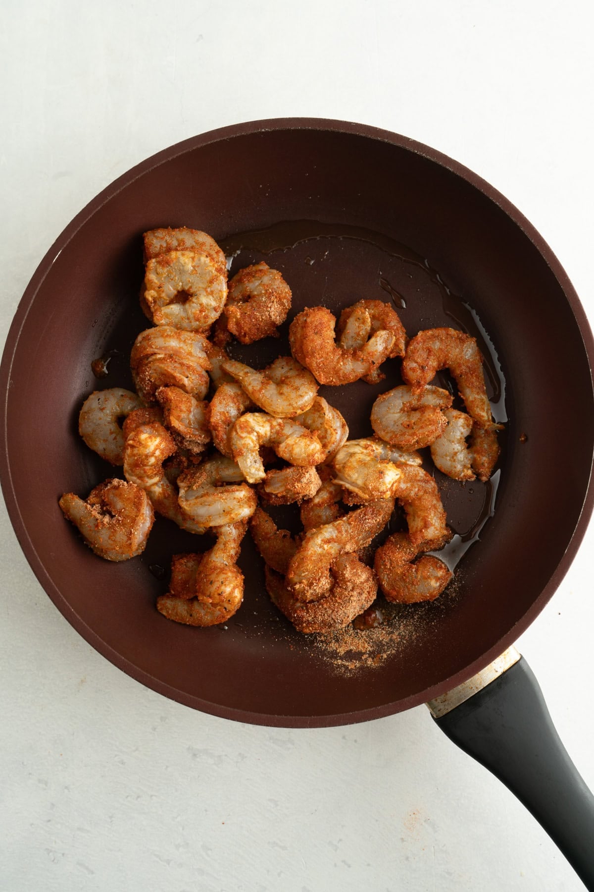 Seasoned shrimp being cooked in a pan.