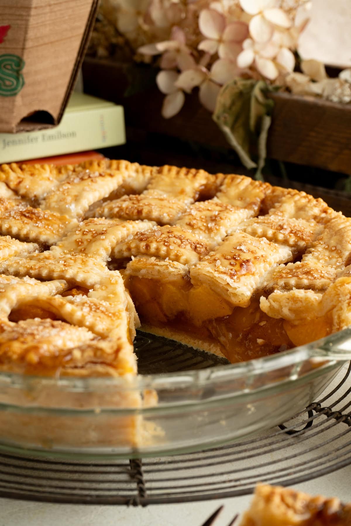 A peach pie recipe on a table with a slice removed.