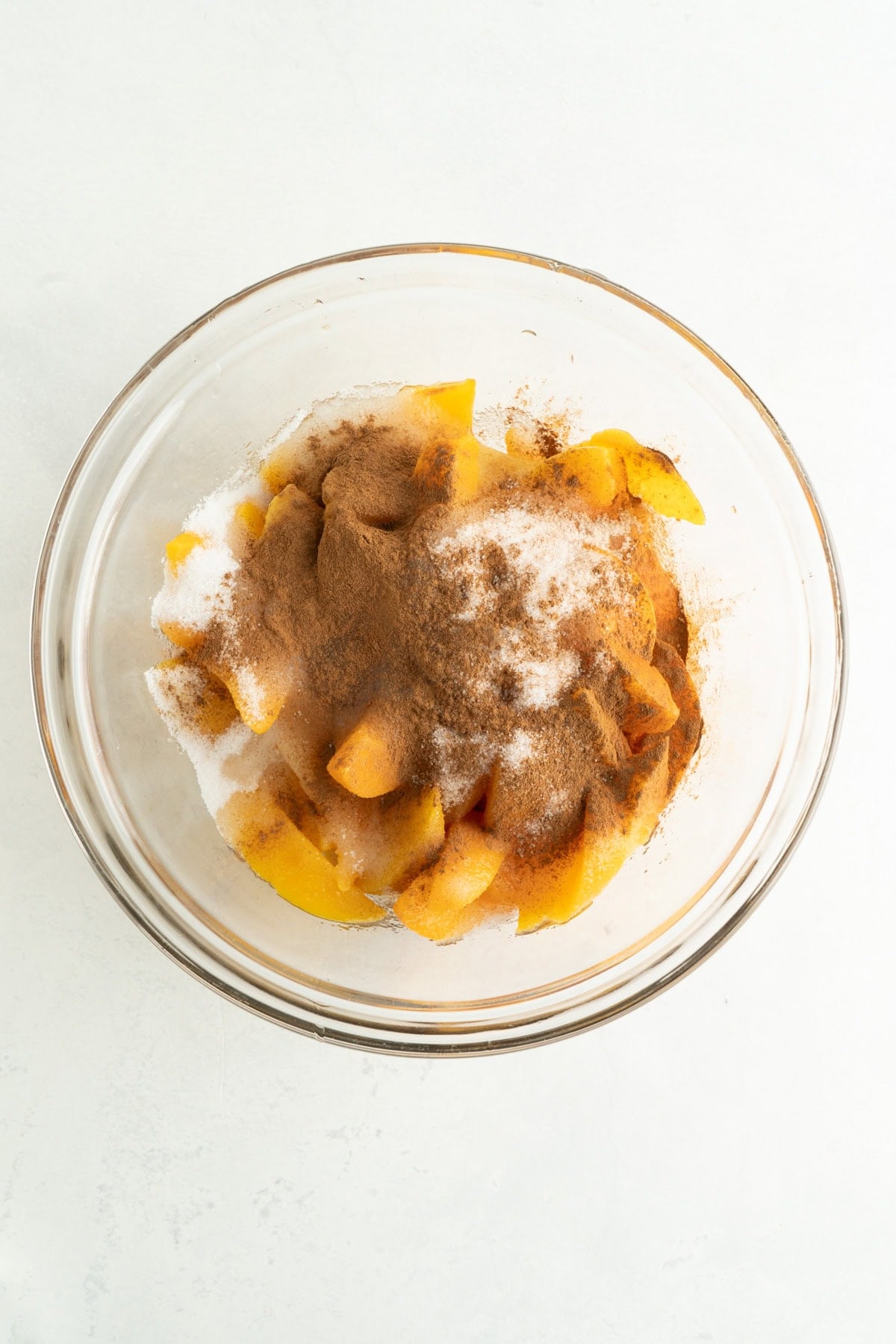 Canned peaches in a bowl with sugar and cinnamon on top.