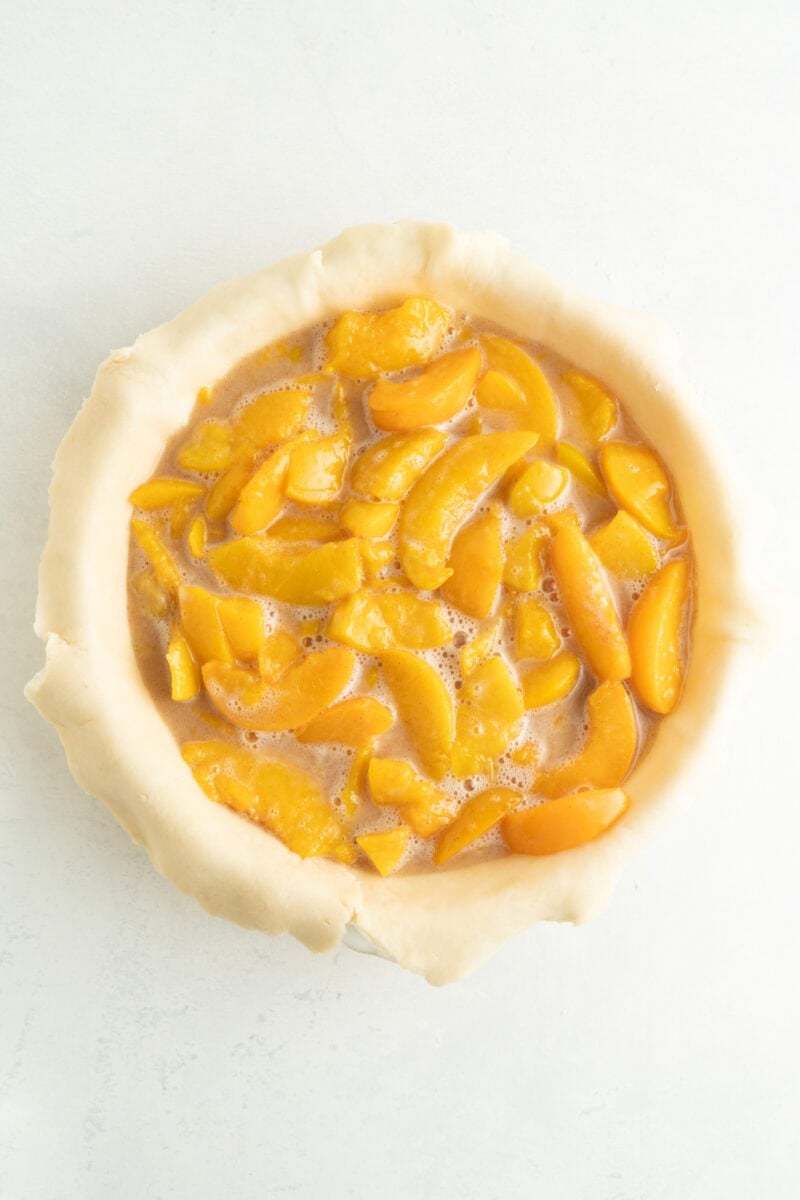 A pie shell with peach pie filling inside.