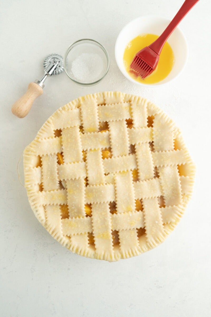 A weaved unbaked pie being egg washed.