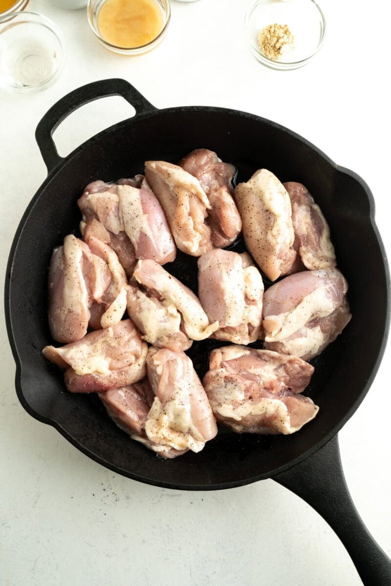 Raw chicken thighs in a cast iron pan.