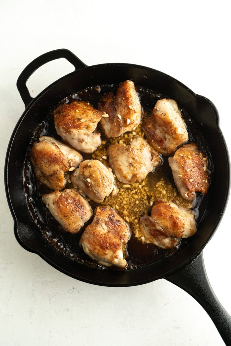 Cooked chicken thighs in  a pan with teriyaki sauce.