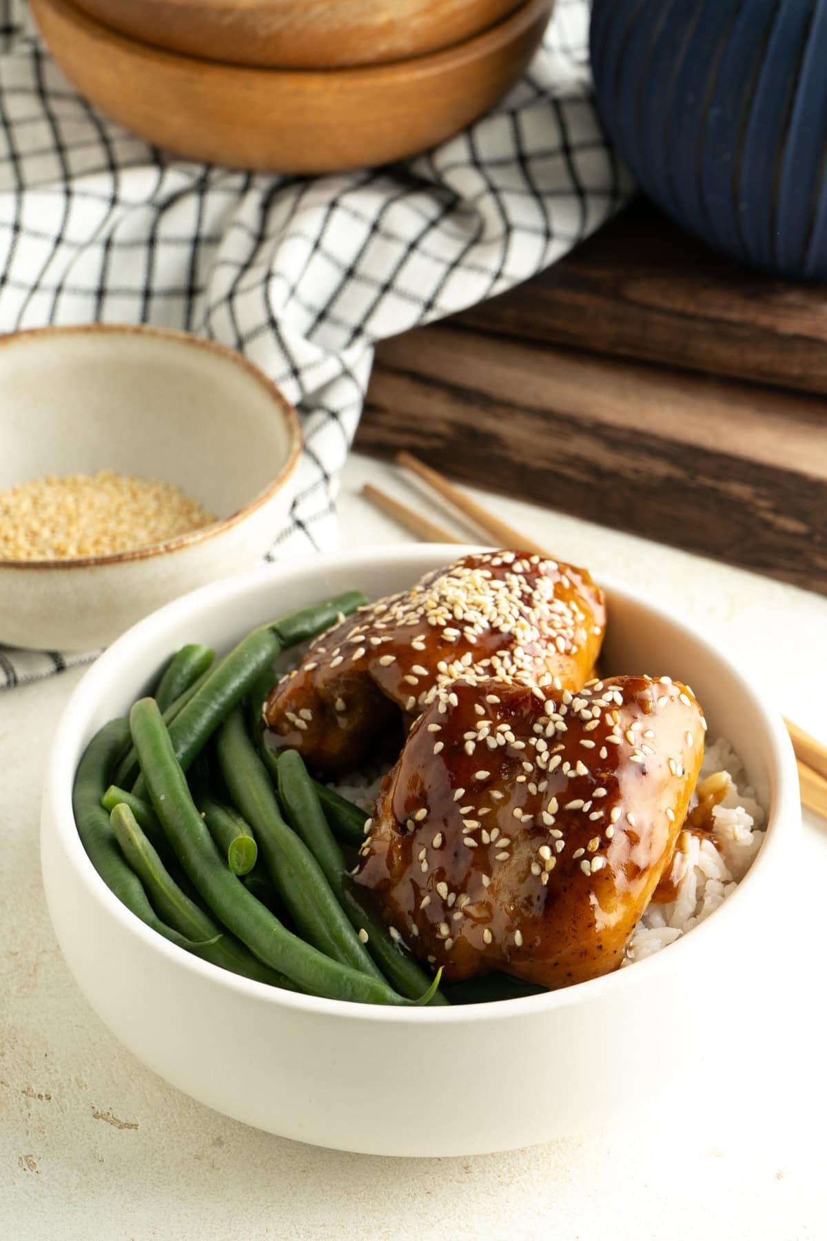 A bowl of teriyaki chicken and rice with beans on a table.