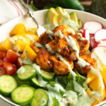A shrimp rice bowl filled with vegetables and topped with a jalapeno dressing.