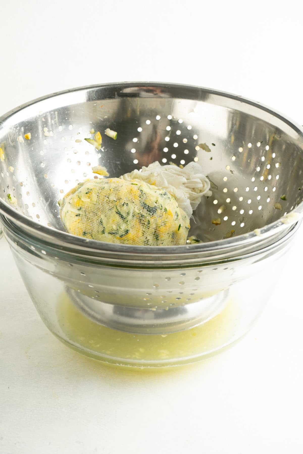 A colander or grated zucchini over a bowl to drain.