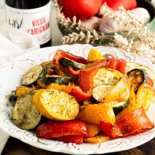 A bowl of roasted zucchini and peppers on a table.