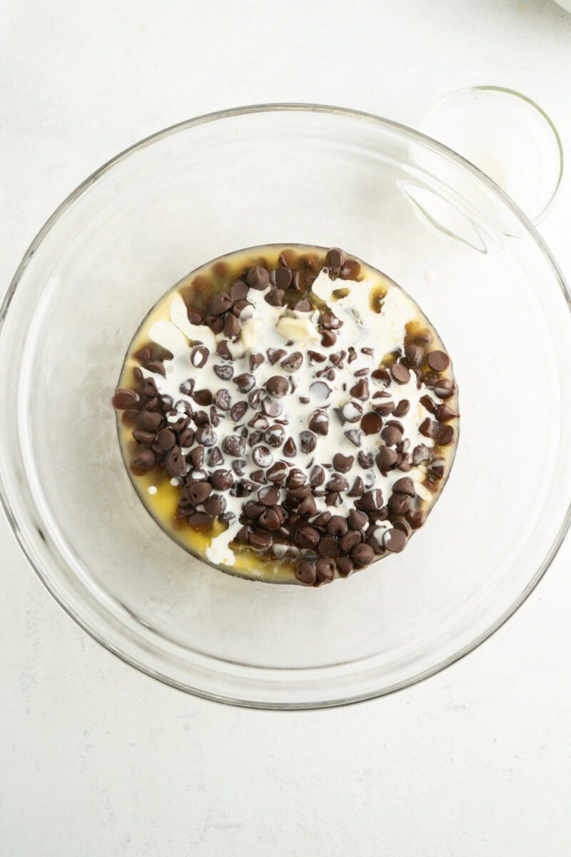 Melted chocolate and butter in a bowl with heavy cream.