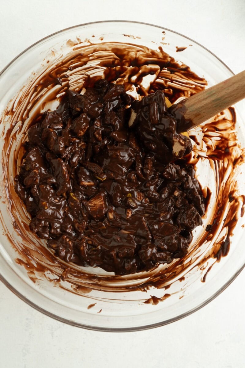 A bowl of melted chocolate mixed with cookies and nuts.