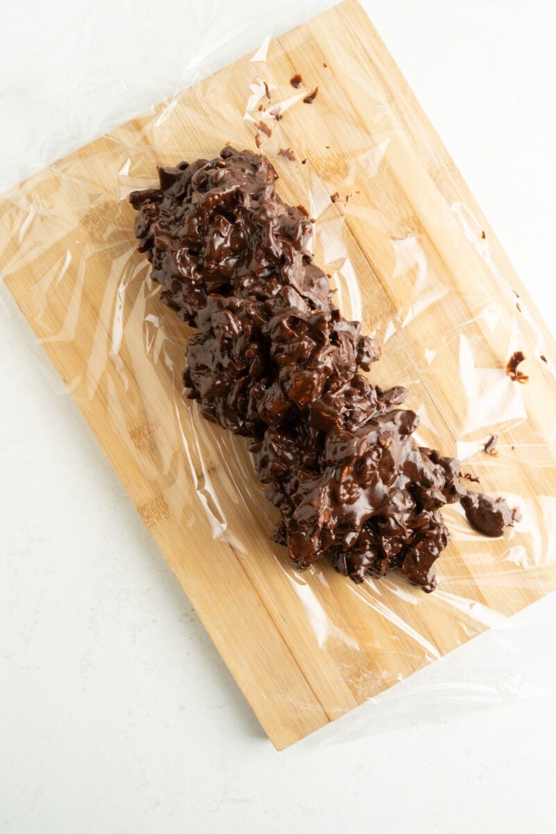 A chocolate, cookie and nut mixture on plastic wrap.
