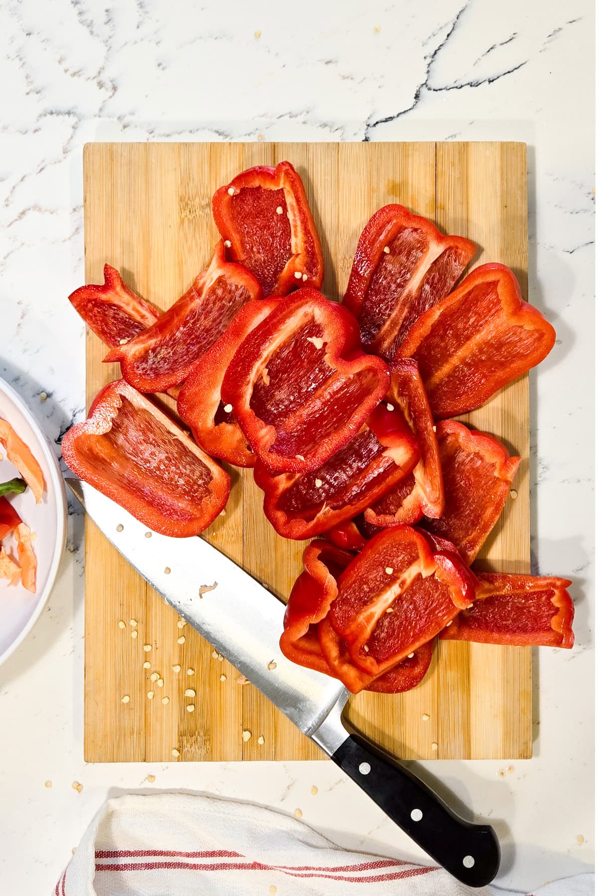 Red peppers being quartered on a cutting board.