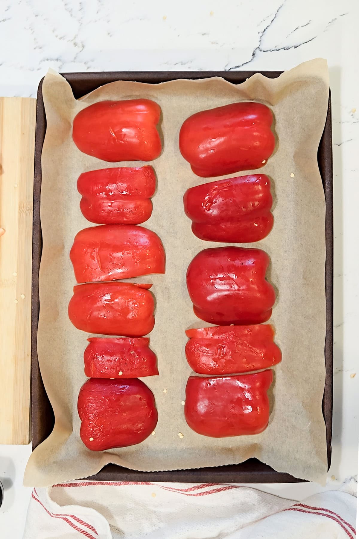Red peppers on a baking sheet lined with parchment paper.