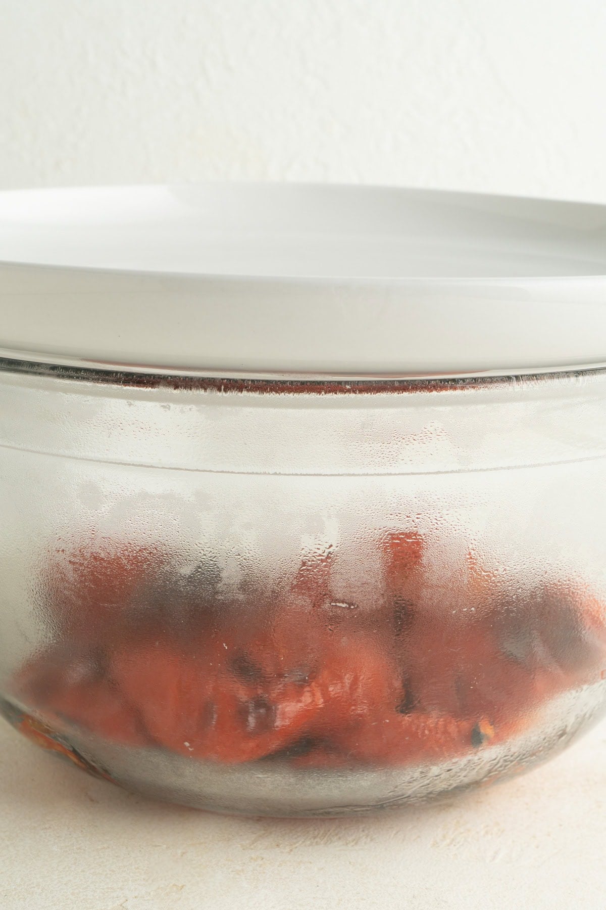 Roasted peppers in a bowl covered with a plate.