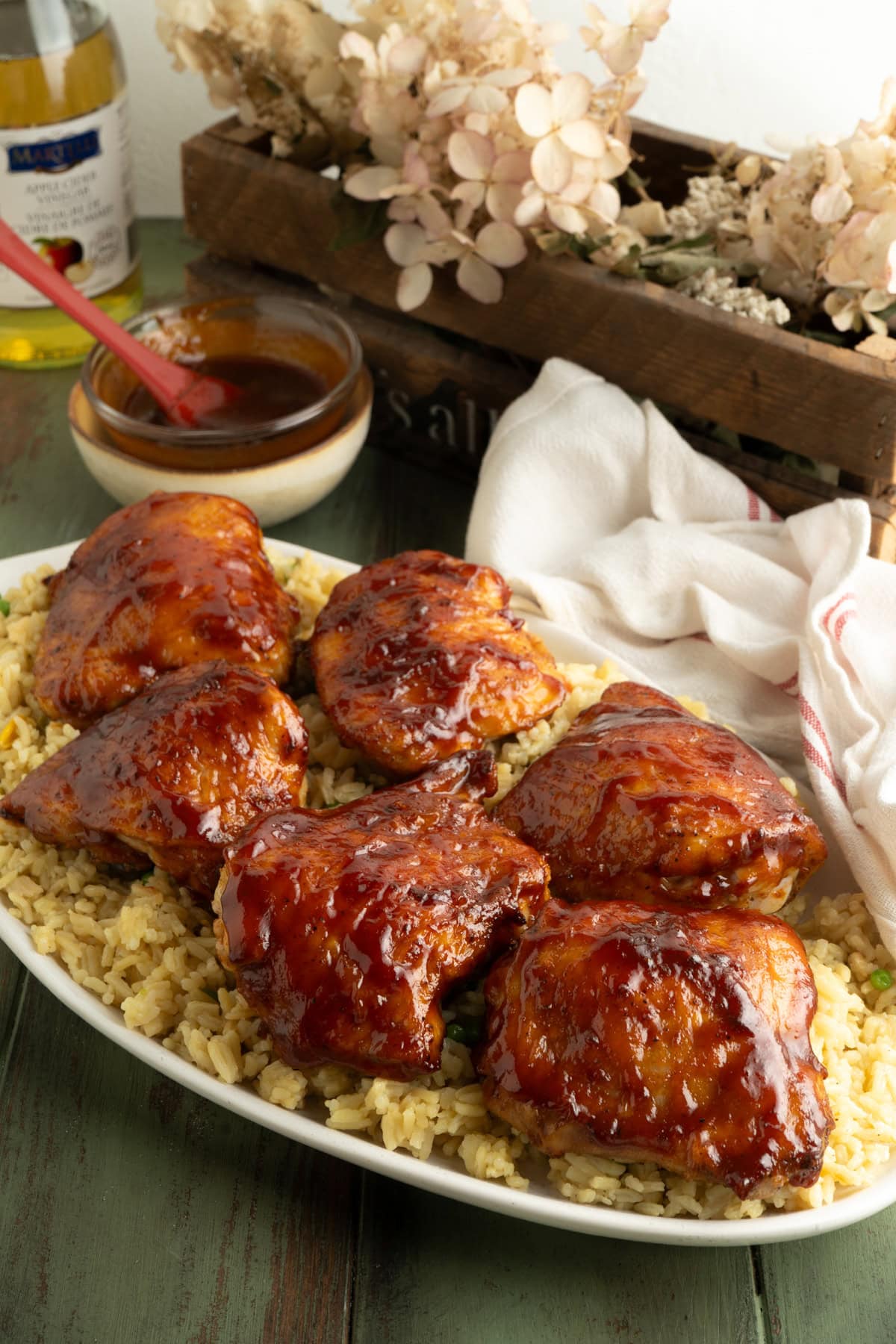A table with a platter of bbq chicken thighs and rice.