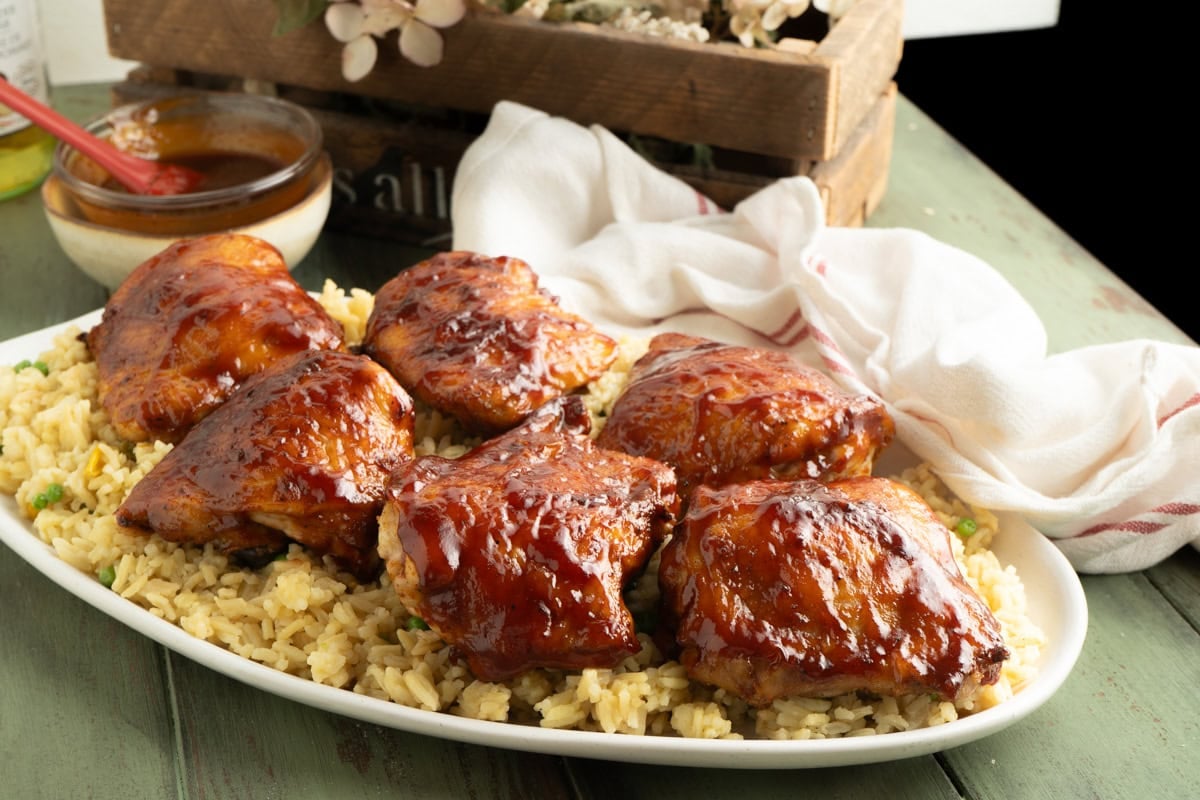 A platter of BBQ air fryer chicken thighs on a bed of rice.
