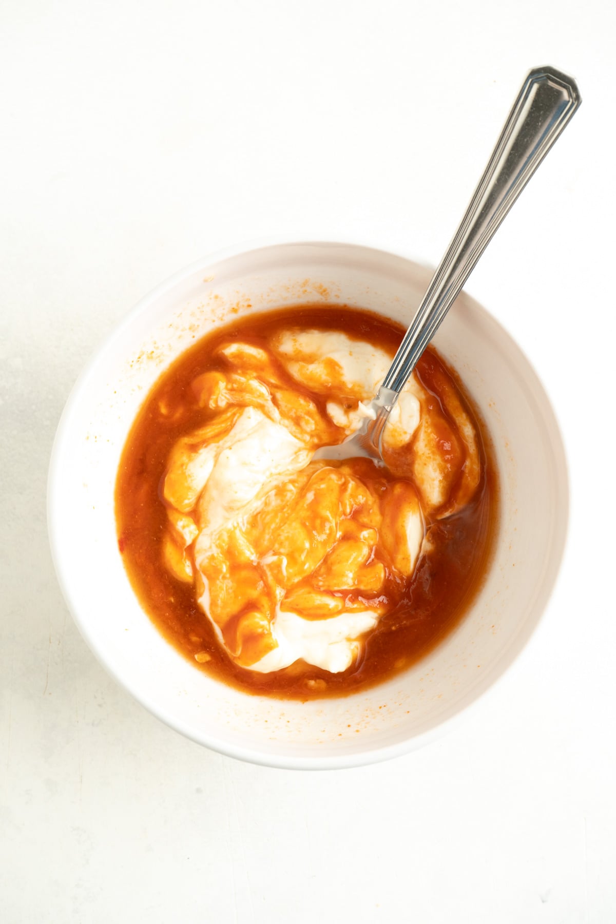 Bang Bang sauce ingredients in bowl being mixed with a spoon.