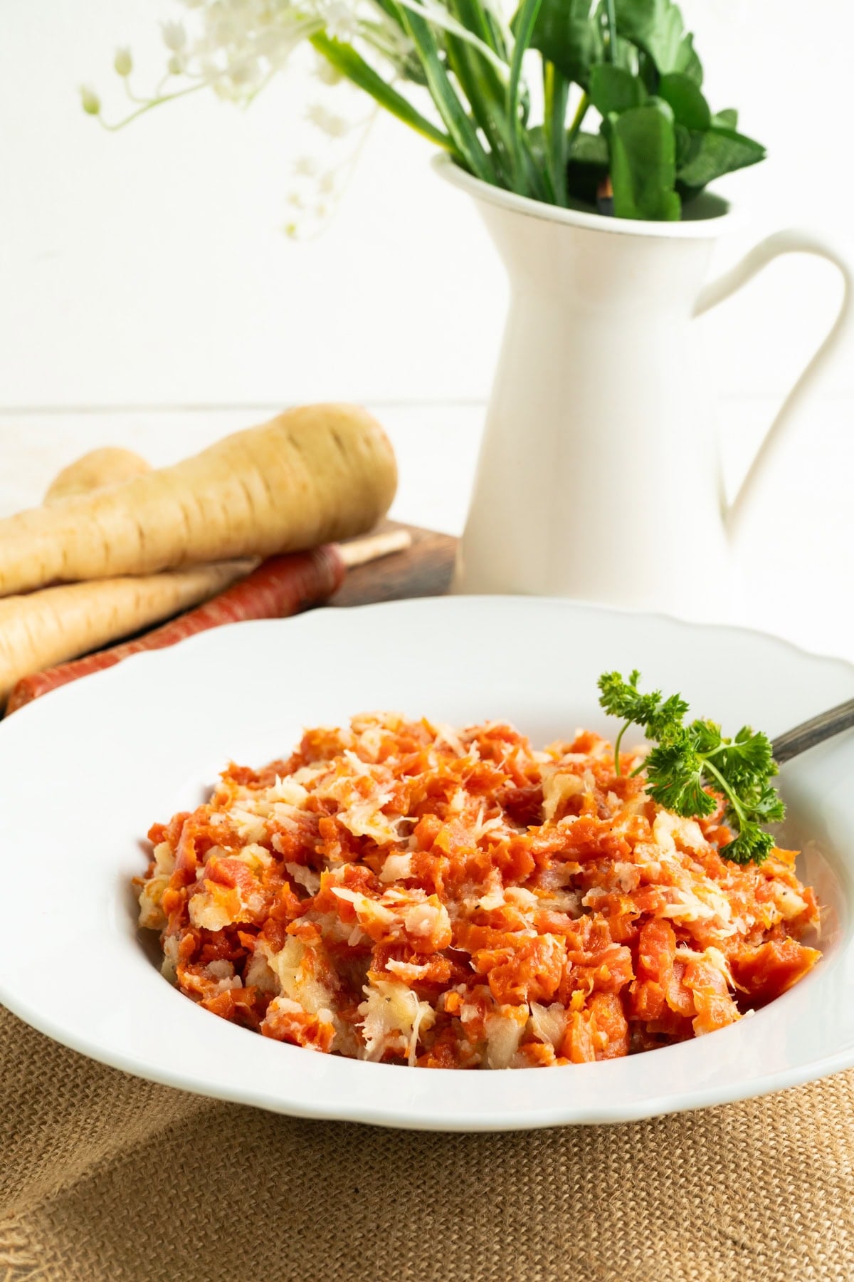A bowl of mashed carrots and parsnips on a dinner table.