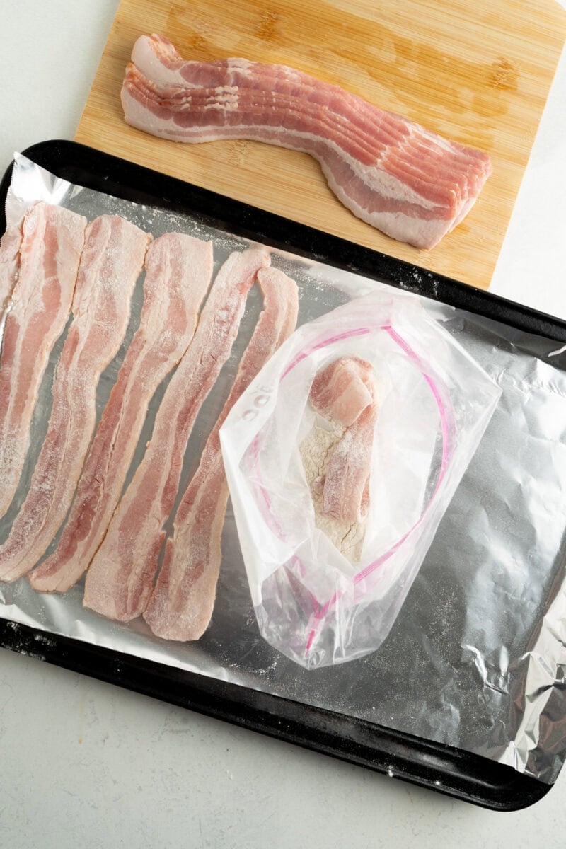 Bacon being dusted with flour and placed on a baking sheet.